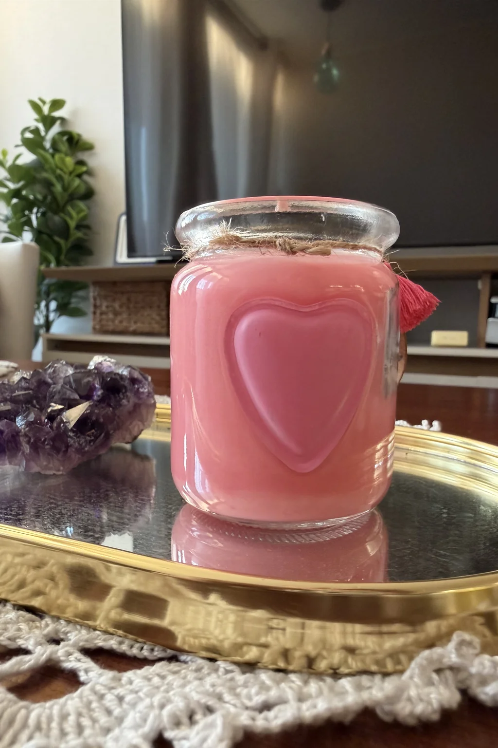 Manos sosteniendo una vela artesanal con forma de rosa rosada